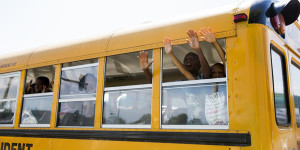 School bus full of children gesture and chant "hands up, don't shoot" as they drive past the scene of where, according to local media, police shot dead a 23-year-old man wielding a knife in the St Louis area