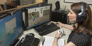 woman sits at computer designing a game and wearing headphones