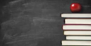 books stacked against a chalkboard with an apple on top