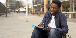 a young student writing in a wheelchair