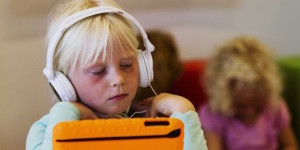 Young girl with headphones playing a game on an ipad