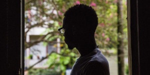 silhouette of young boy standing in front of window