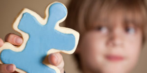 Boy Holding Blue Iced Puzzle Piece Cookie