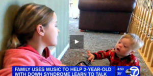 toddler with Down Syndrome singing with sister playing guitar