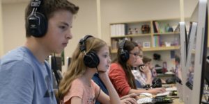 group of students with headphones looking at computers