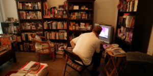 adult staring at computer surrounded by books