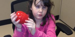 girl holding up red modified easter egg
