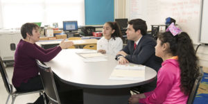NC supe with students and educator in meeting