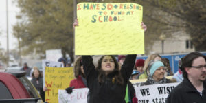 student holding sign wanting to go to school