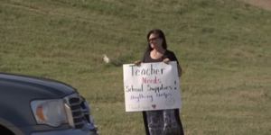 teacher holding up a sign asking for money