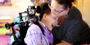 girl in wheelchair crying with caregiver